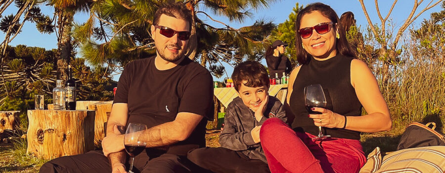 Caio, Carla e Ricardo sentados em uma toalha de pic-nic ao por do sol