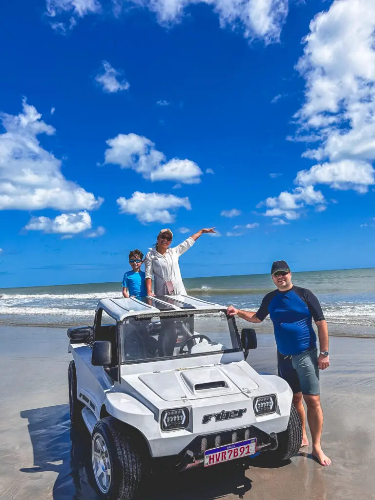 Caio, Carla e Ricardo em bug branco com o mar de Jeri ao fundo