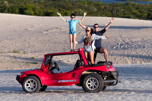 Carla, Caio e Ricardo em Bug vermelho com uma linda vista do fundo de dunas , lagoas e vegetação nas dunas do lado leste de Jeri