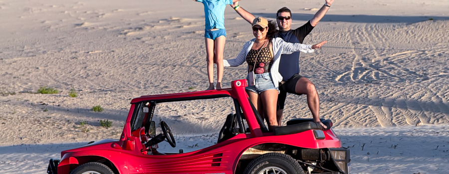 Carla, Caio e Ricardo em Bug vermelho com uma linda vista do fundo de dunas , lagoas e vegetação nas dunas do lado leste de Jeri
