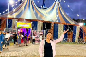 Carla com imagem de circo ao fundo