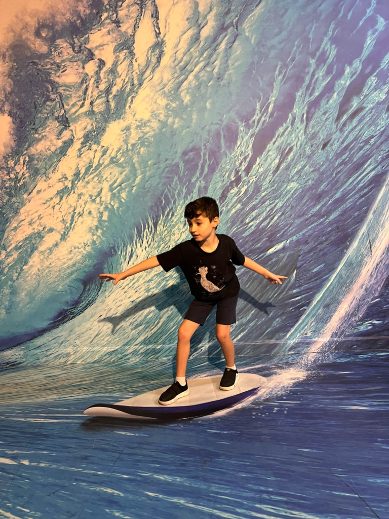 Caio simulando estar surfando no Museu das Ilusões